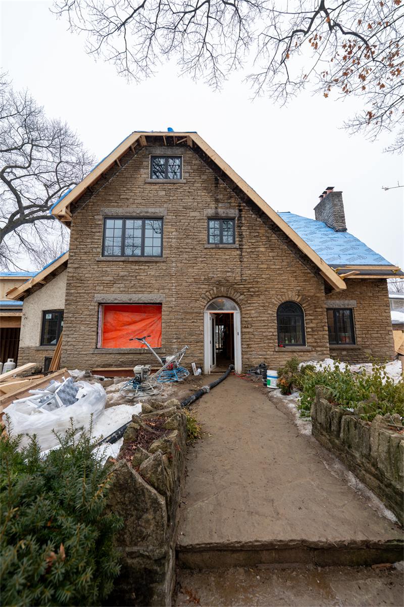 Large stone home addition under construction with a new masonry walkway being finished in the foreground