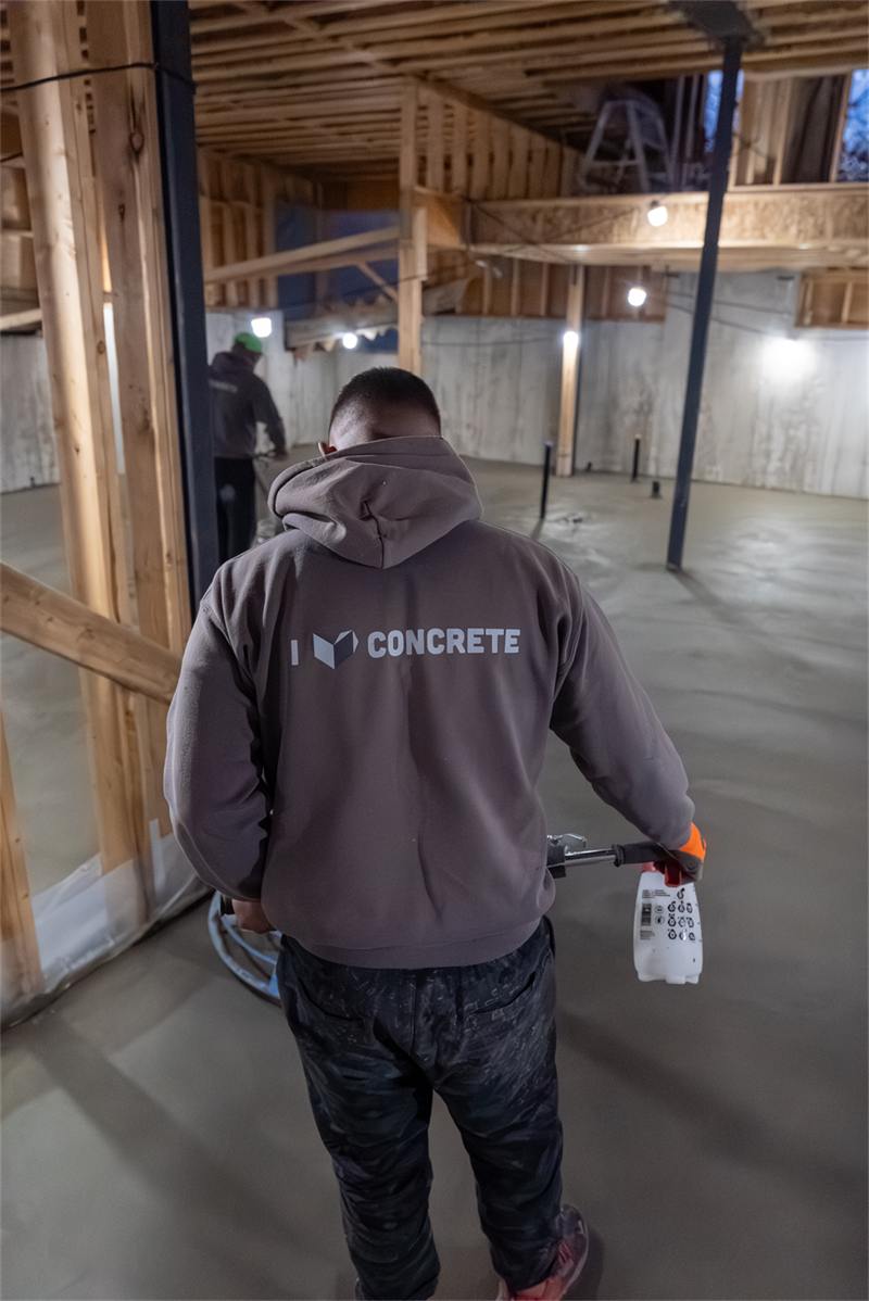 Crew member walking a finished basement floor with a sprayer