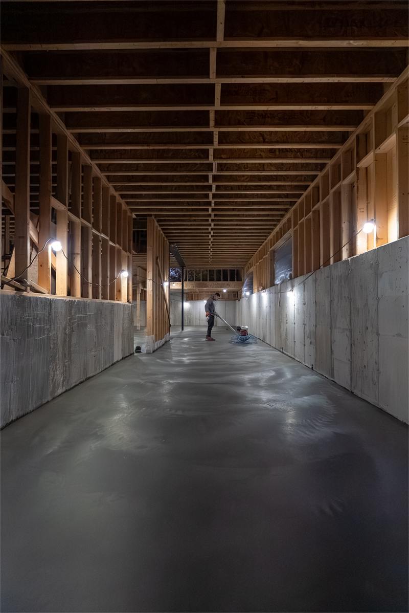 Freshly poured and power-trowelled basement floor along a finished foundation wall