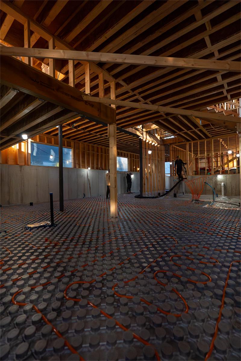 Radiant heating panel system with orange PEX tubing laid across a framed basement sub-floor