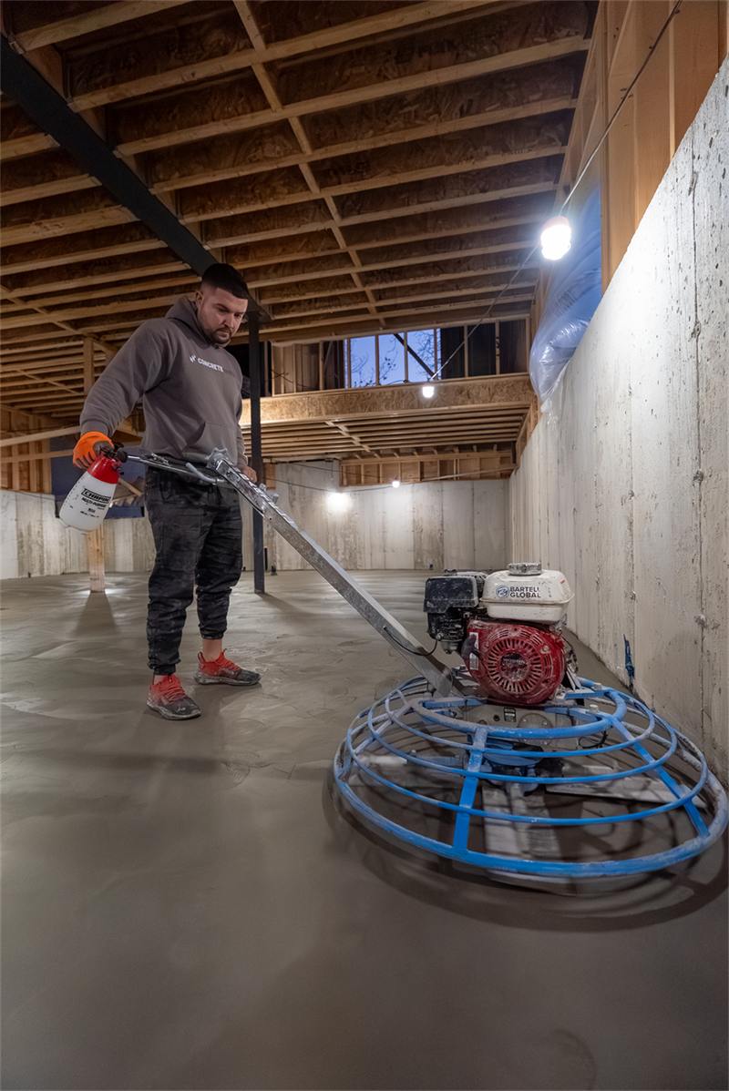 Power trowel finishing a freshly poured basement floor to a smooth, level surface