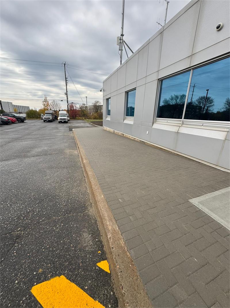 Poured concrete curb along a commercial parking lot, tied into a paver walkway at the building entrance