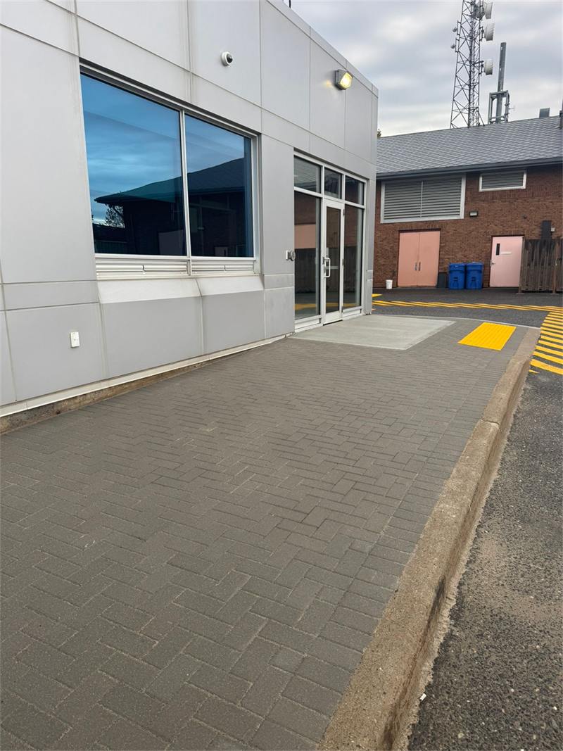 Commercial building entrance with a paved walkway and yellow tactile strip