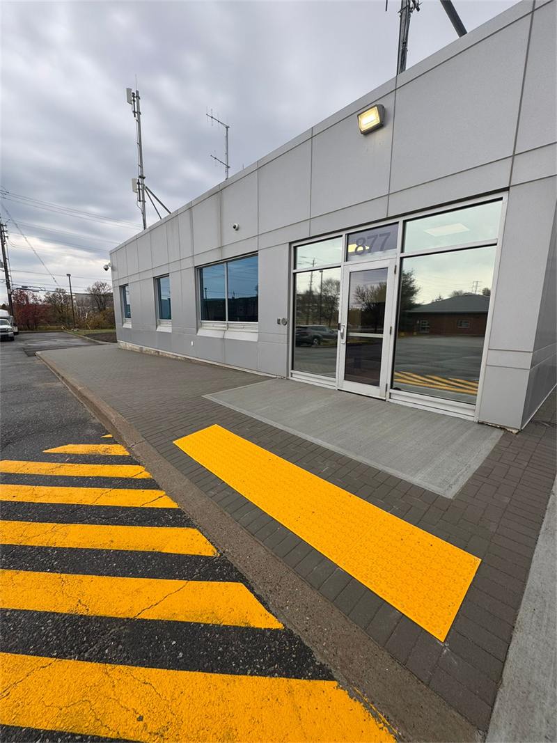 Yellow tactile accessible ramp leading to a commercial building entrance