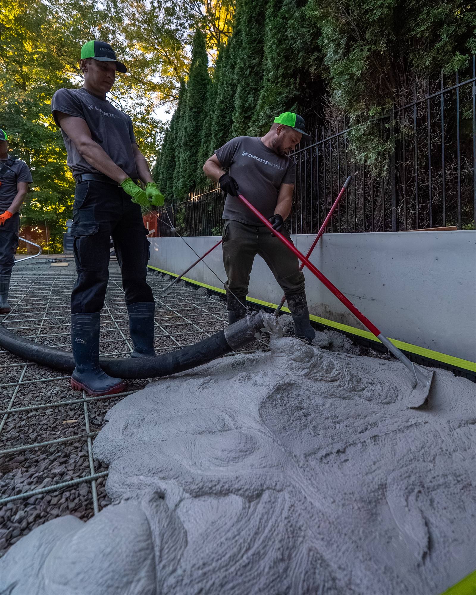 Two crew members raking granular base into place before a pour
