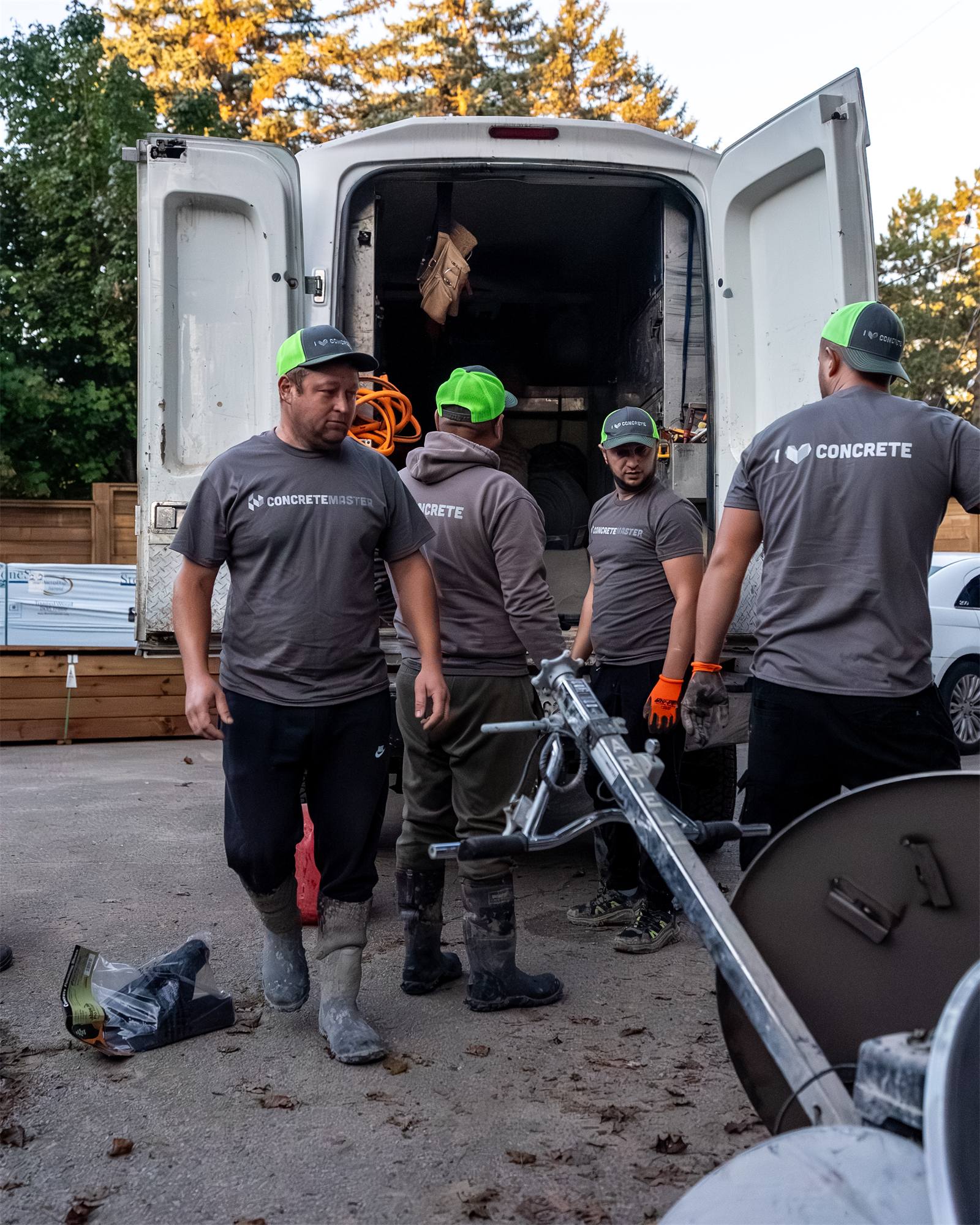 Four Concrete Master crew members unloading equipment from the back of a van