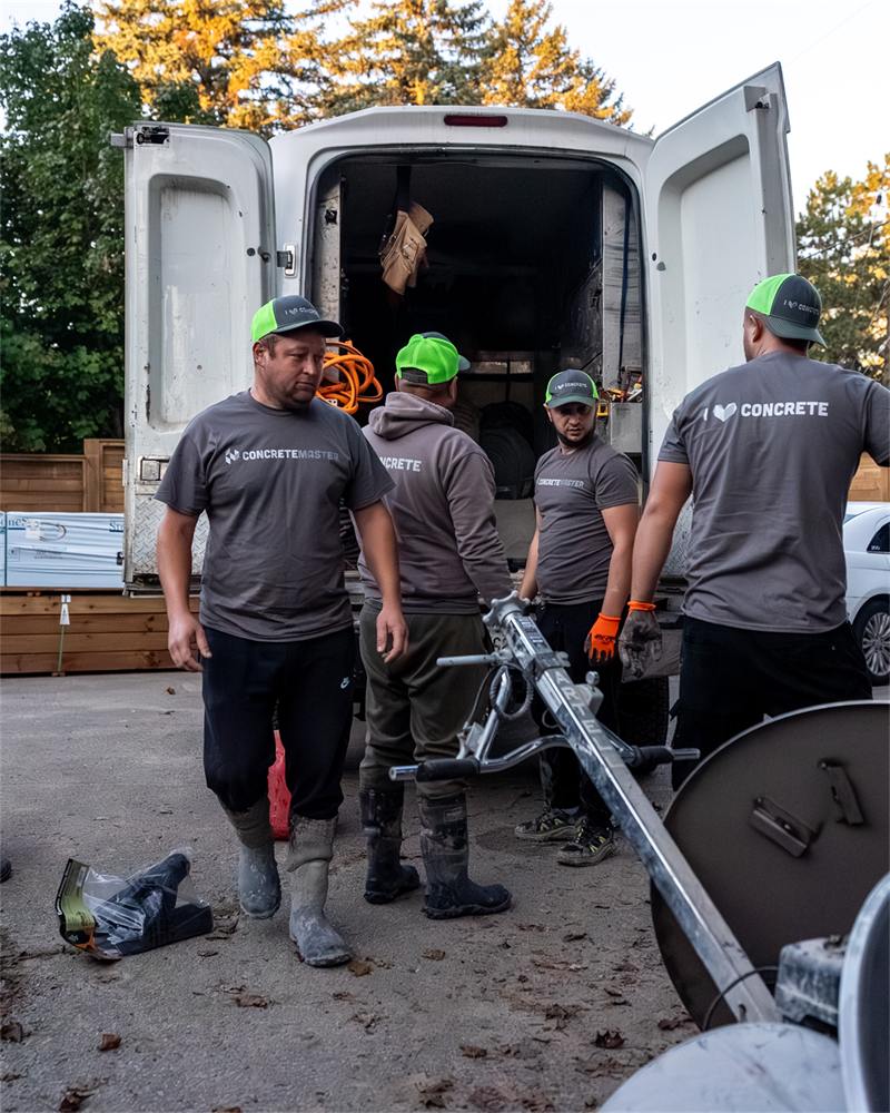 Four Concrete Master crew members unloading equipment from the back of a van