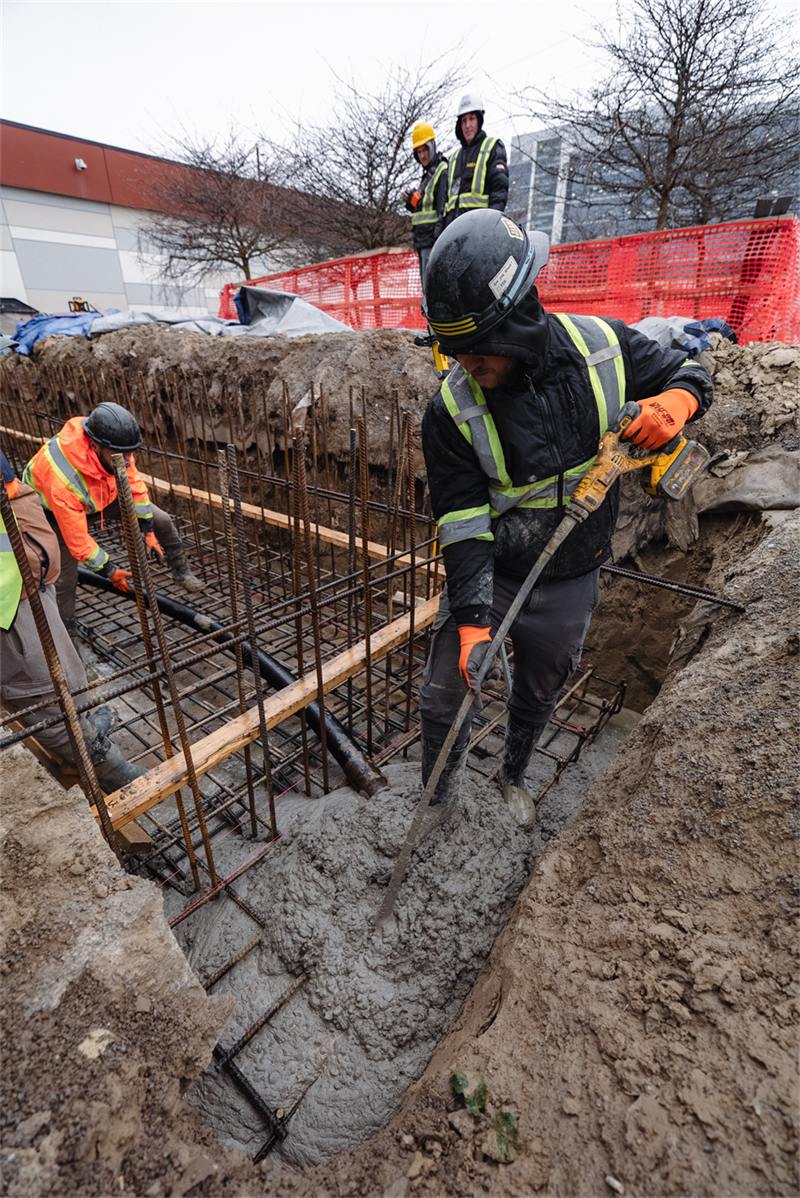 Crew placing and vibrating concrete delivered by pump hose into a reinforced footing