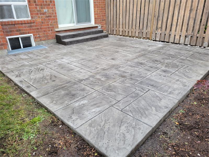 Stamped concrete patio and step in a fenced back garden
