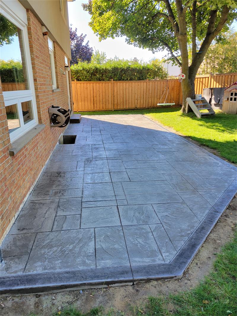 Large stamped concrete patio in a York-stone pattern beside a brick house