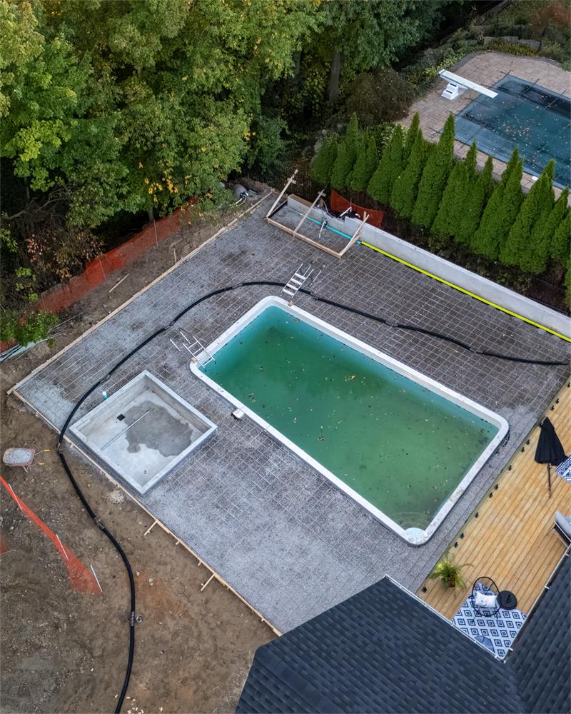 Aerial view of a swimming pool surrounded by a freshly poured concrete deck