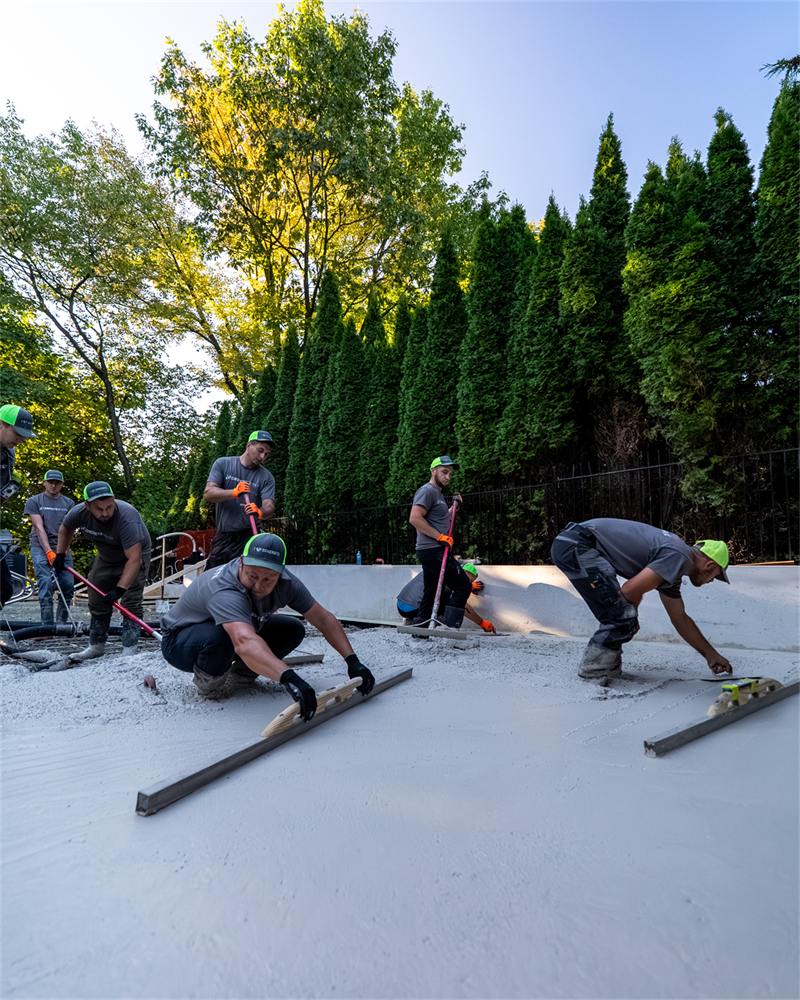 Crew screeding a freshly poured concrete pool deck