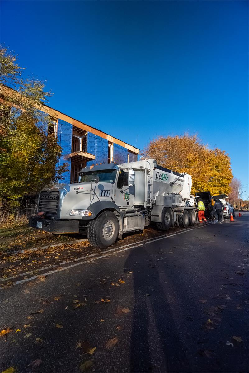 Concrete mixer truck delivering to a framed job site on a residential street
