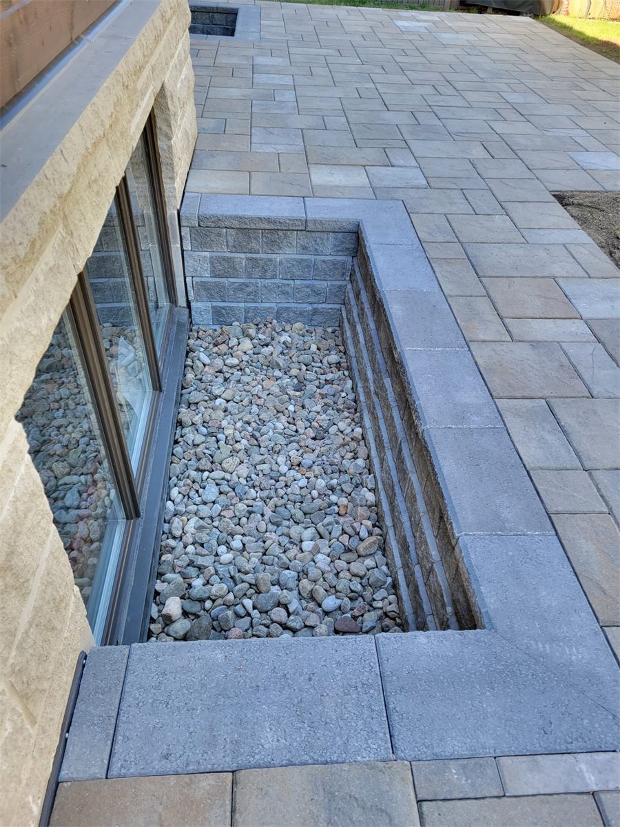 Basement window well and waterproofing work along a foundation wall